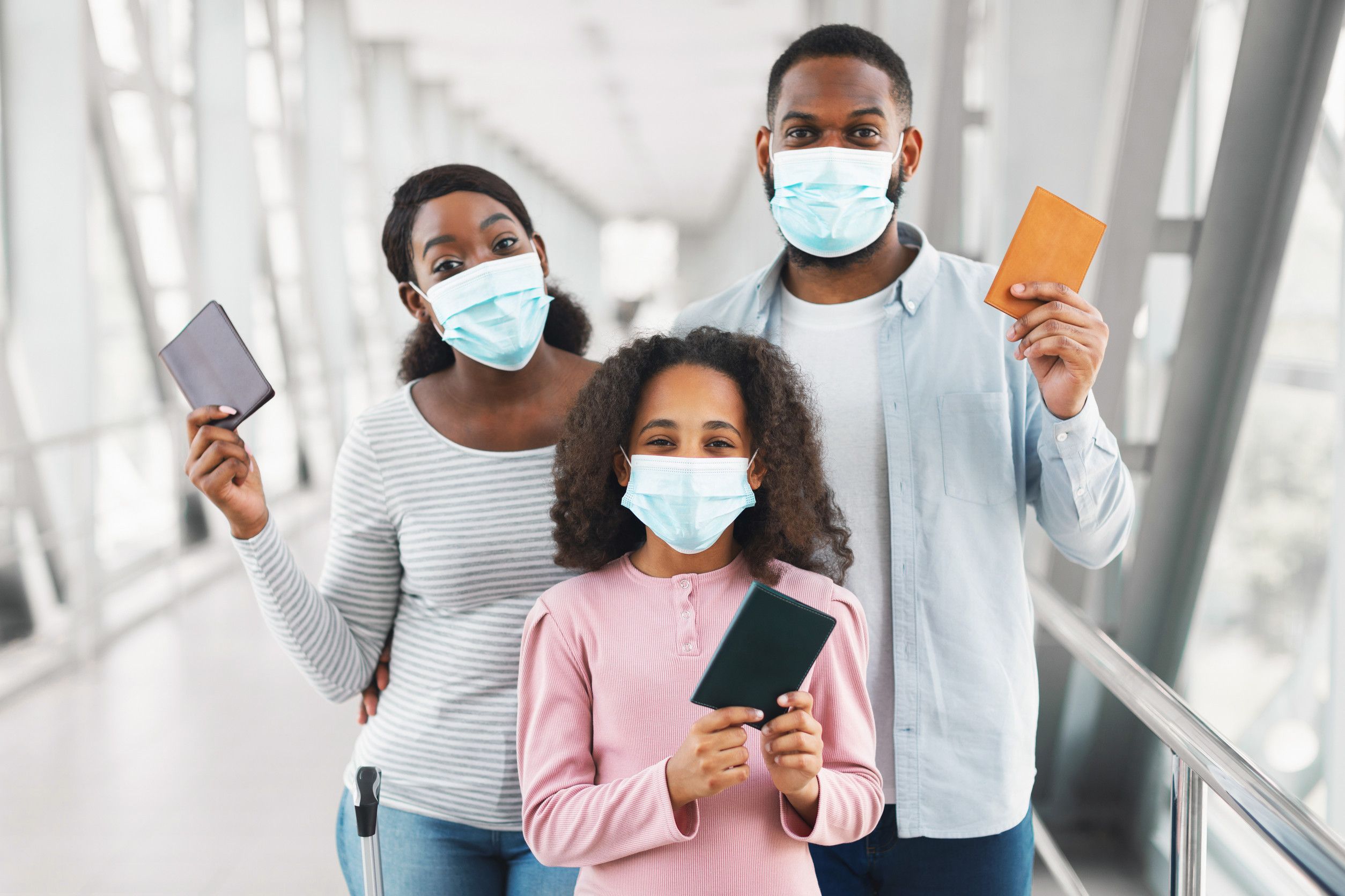 Black Family In Masks Traveling Holding Documents In Airport