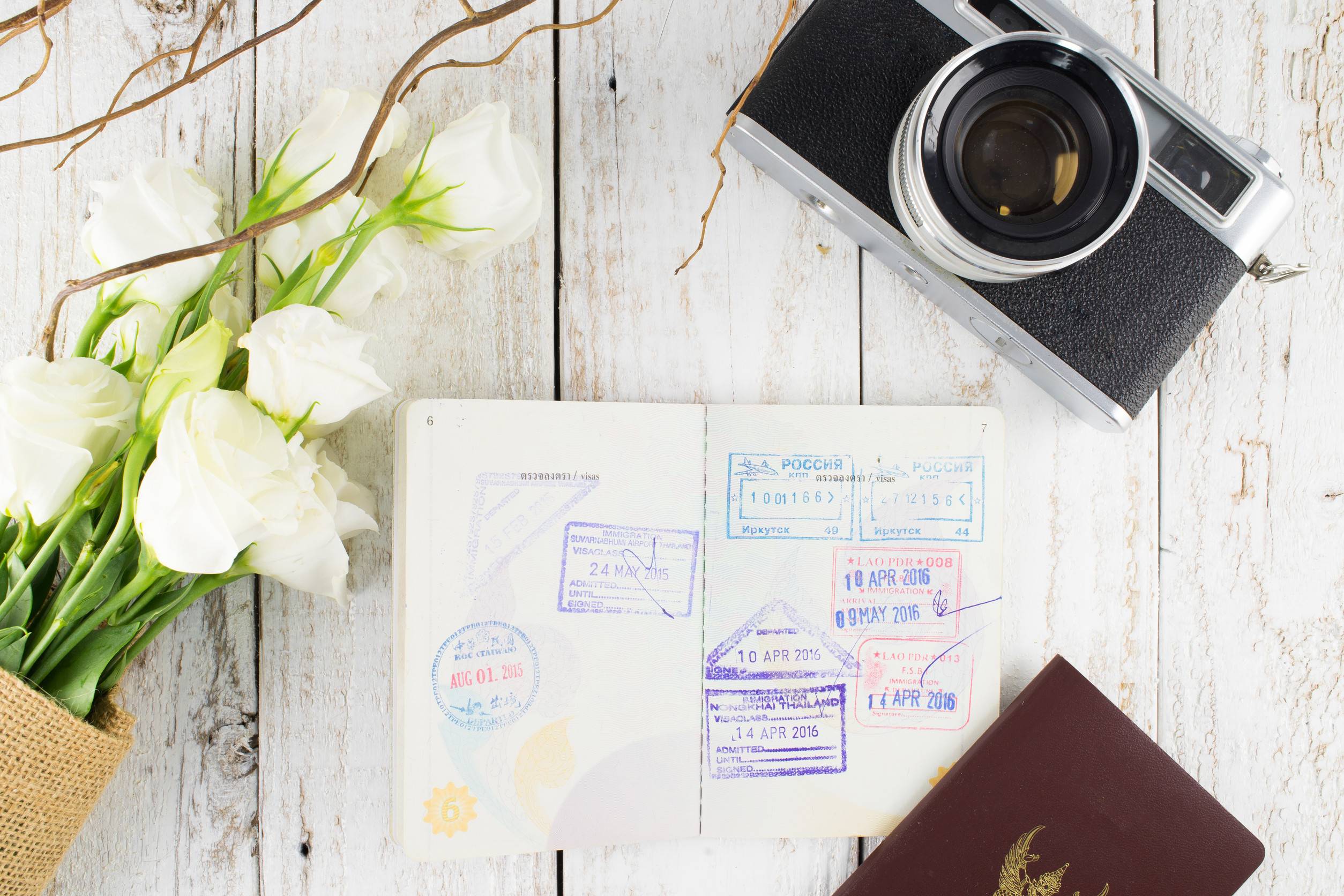 Camera Passport And White Bouquet On White Wooden