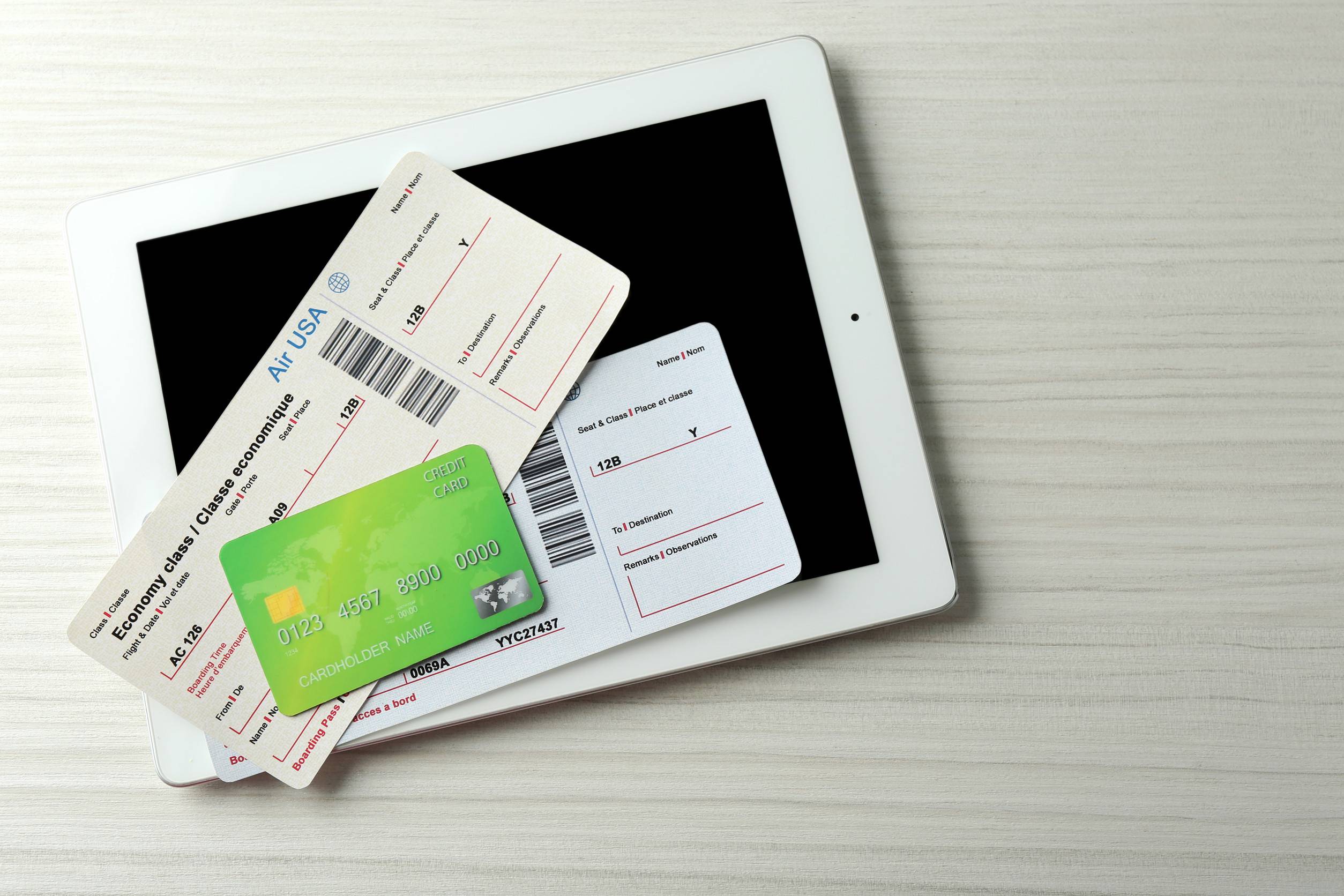 Tablet With Credit Card And Flight Tickets On Light Wooden Table